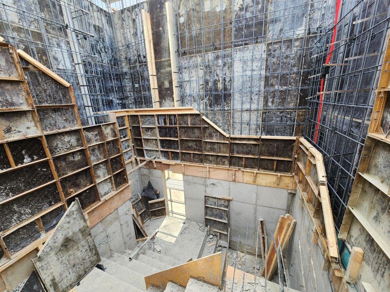 거푸집으로 둘러 쌓인 콘크리트 계단이 보이고, 군데 군데 철골이 노출되어 있다.