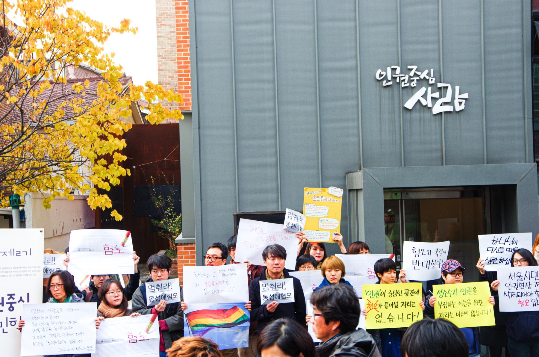 인권중심사람이라는 현판이 걸린 건물 앞에 십수명의 사람들이 피켓을 들고 서 있다.